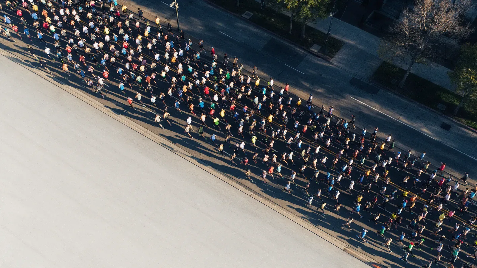 Aerial view of a dense stream of runners along a wide city avenue on a winter morning